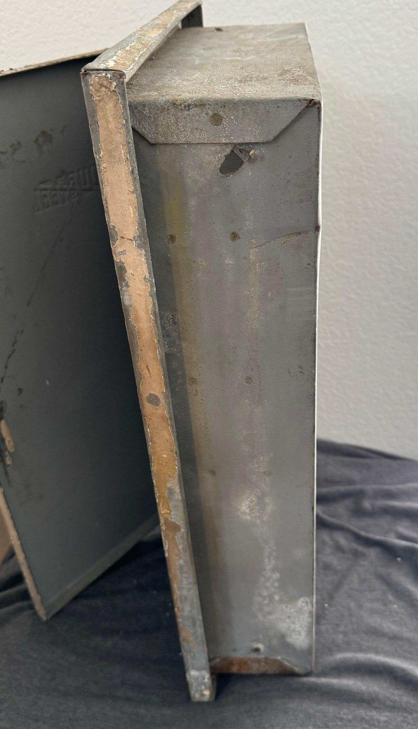 Rust-covered metal box on a gray surface with a white background