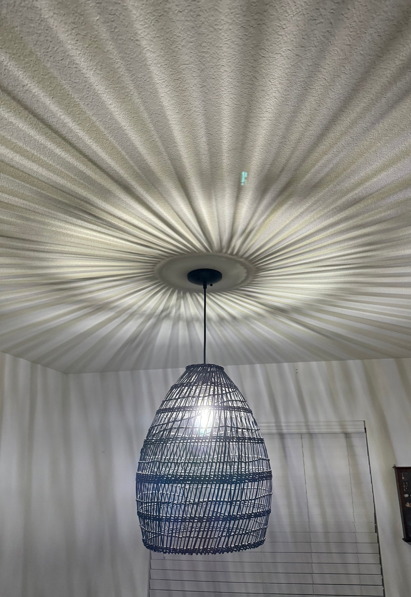 Woven pendant light fixture hanging from a textured ceiling