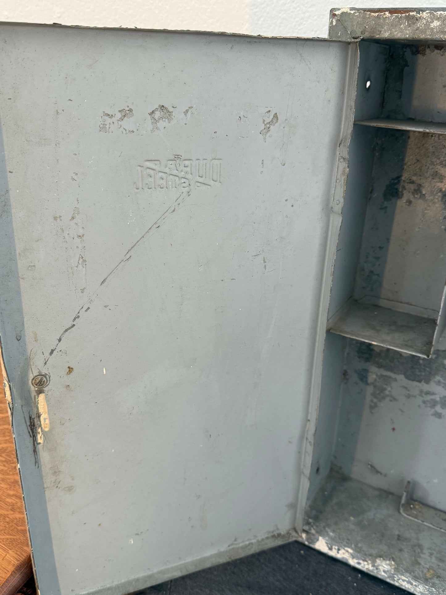Metallic surface with text and wear, possibly a lid or cover of a container.