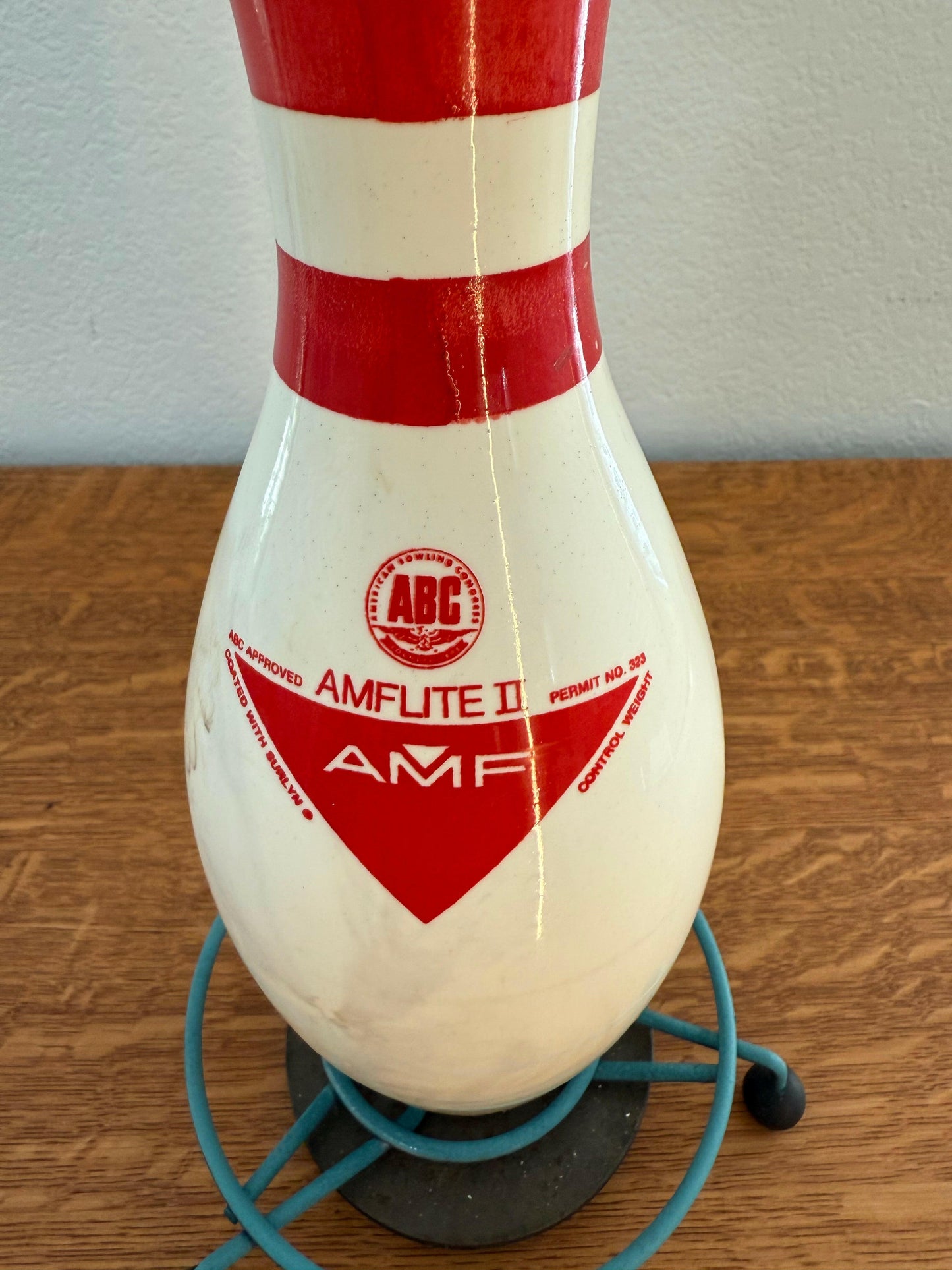 Red and white striped bowling pin with AMF logo on a wooden wall.