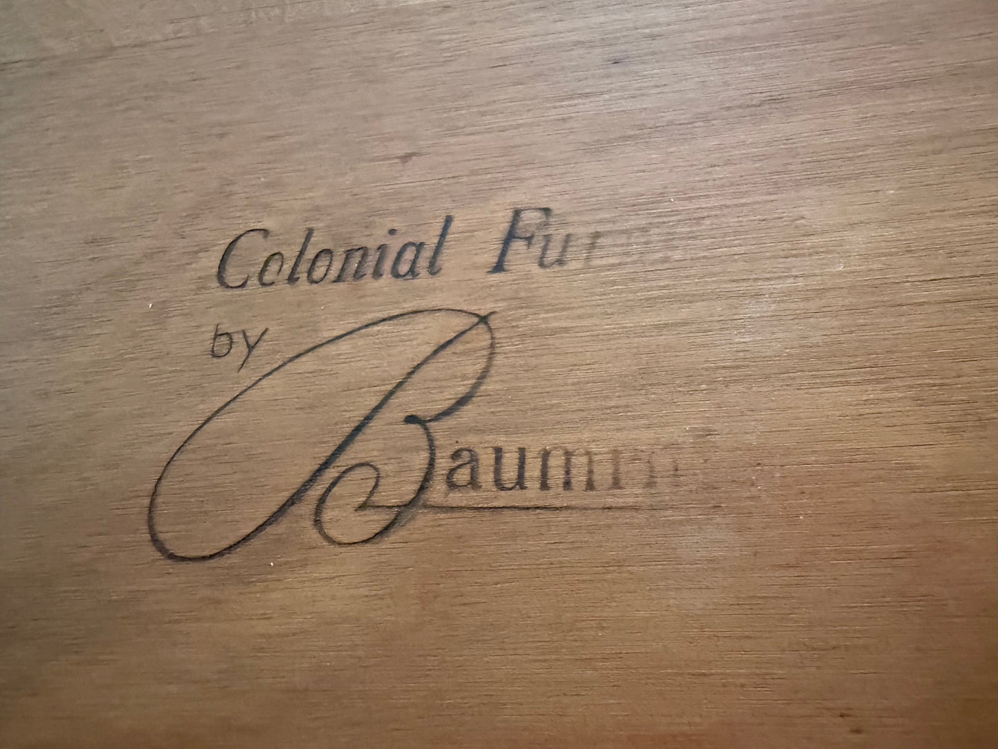 Wooden surface with 'Colonial by Baumm' engraved text