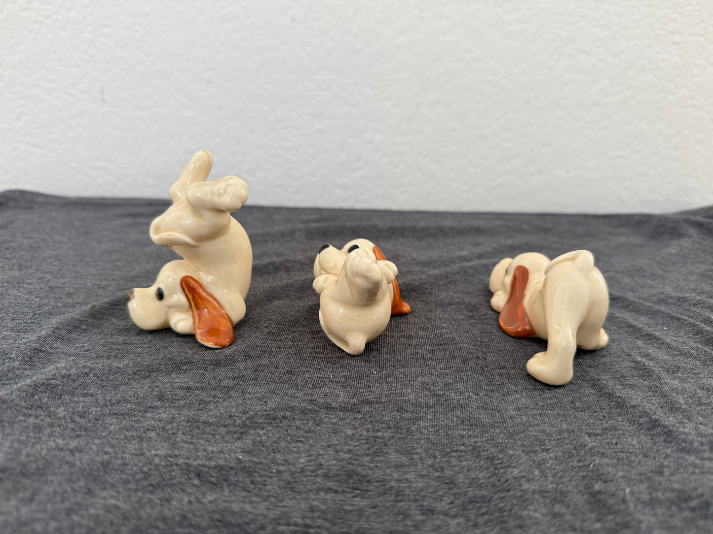 Three ceramic dog figurines on a gray surface with a light blue background