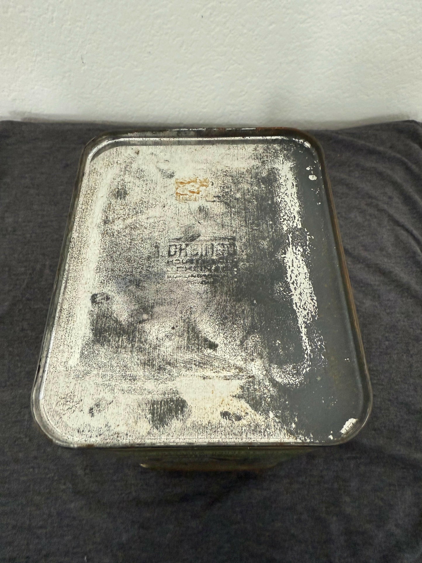 Vintage metal box with a brand logo on a dark surface