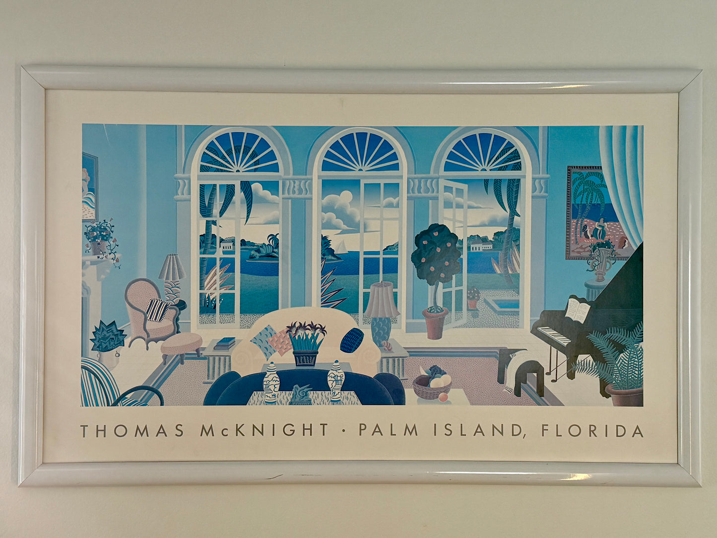 Framed artwork of a room with large windows, furniture, and decor.