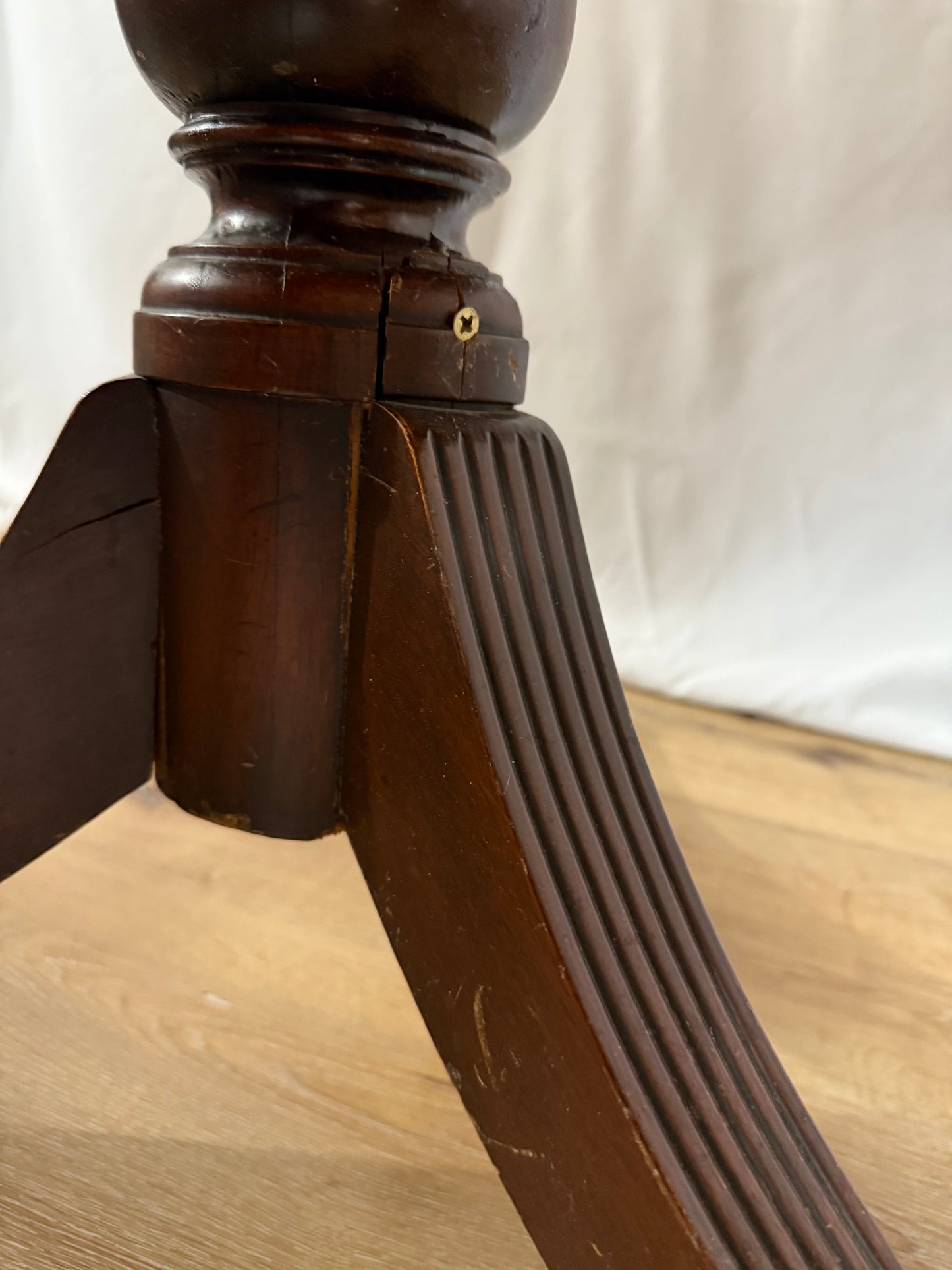 Close-up of a wooden leg with a ribbed design on a light wood floor.