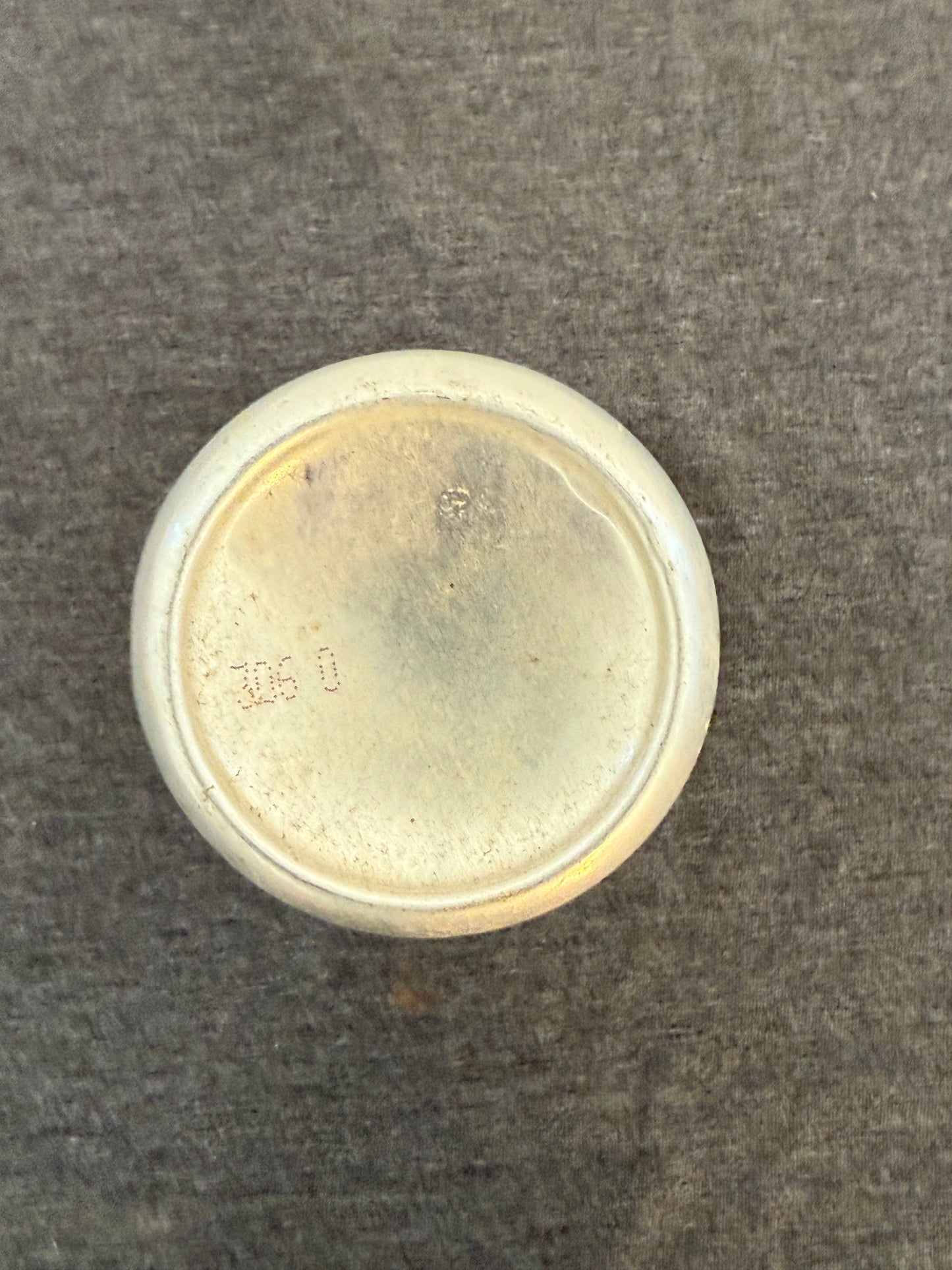 Round metallic object on a textured gray background