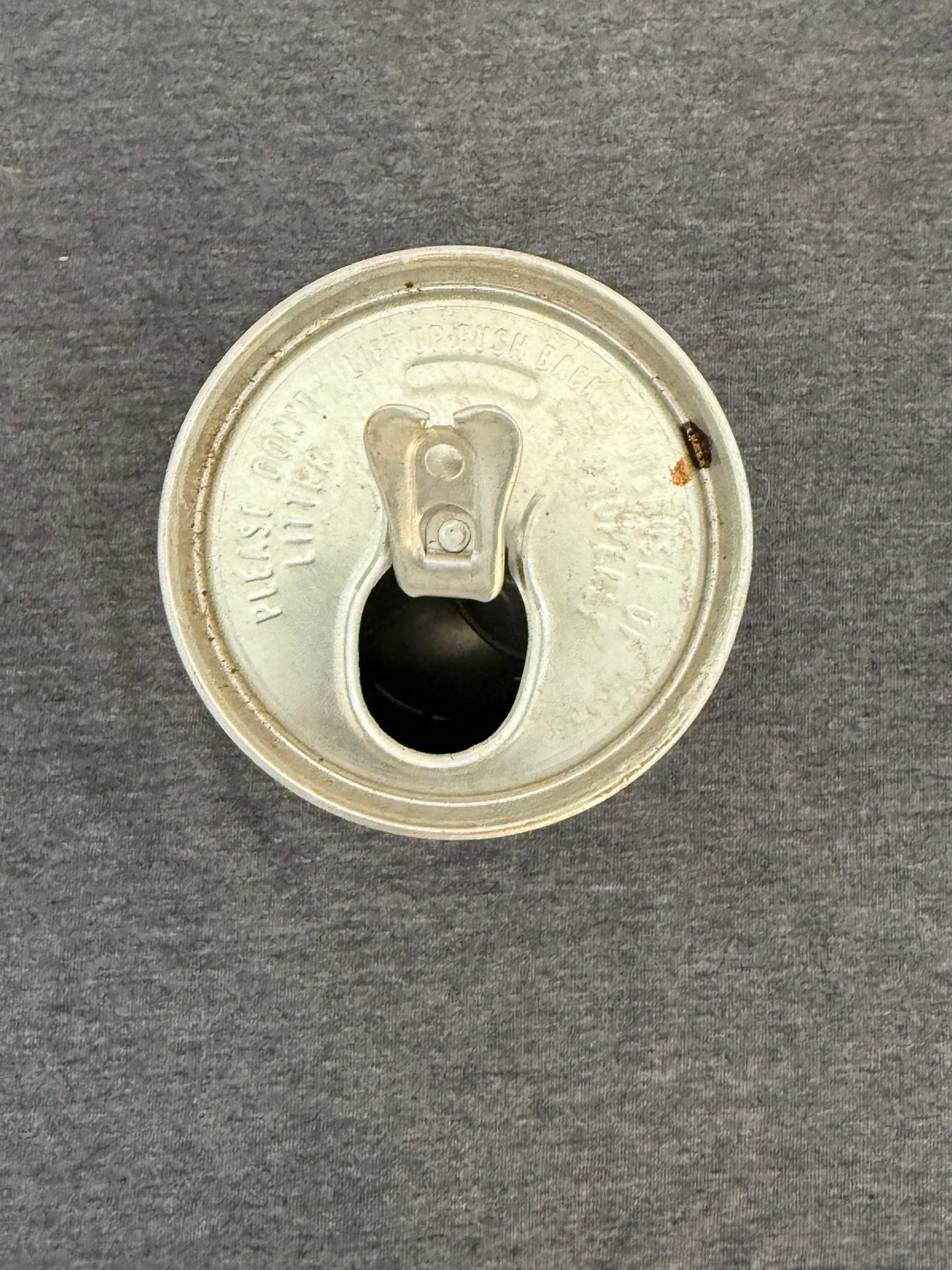 Top view of a metal can lid on a gray background