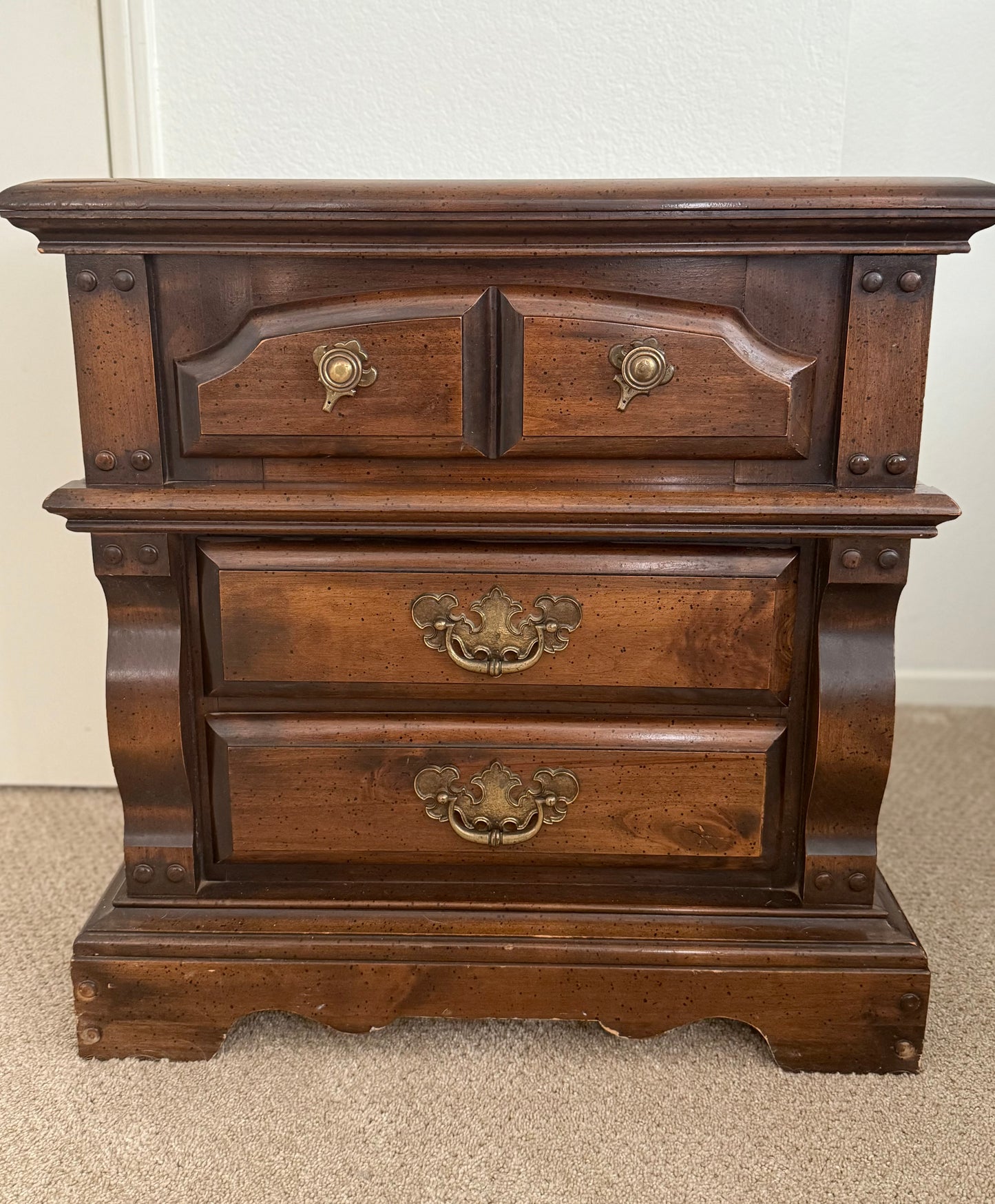 Wooden dresser with three drawers and brass handles on a plain background