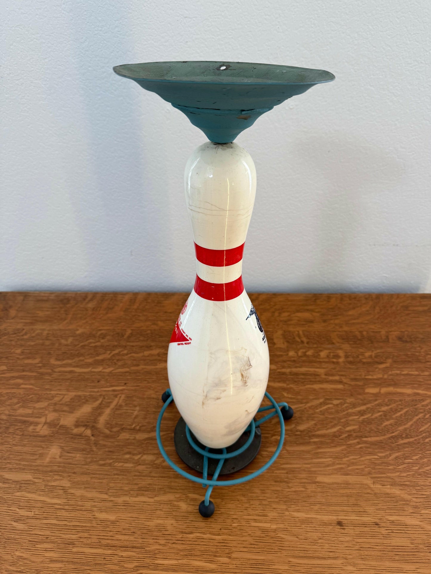 Decorative bowling pin with a character design on a wooden surface.