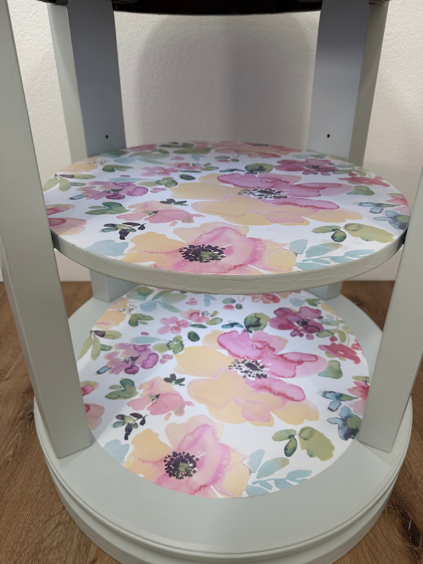 Floral-patterned shelves on a side table with a wooden floor background