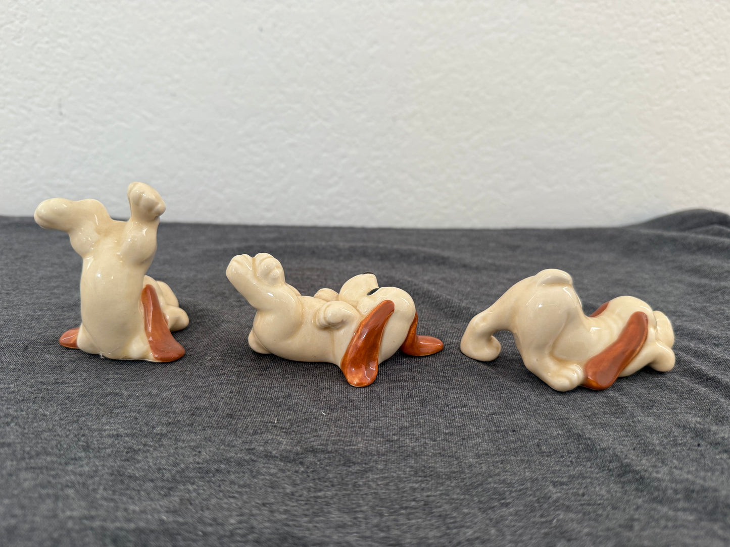Three ceramic dog figurines on a gray surface with a white textured background