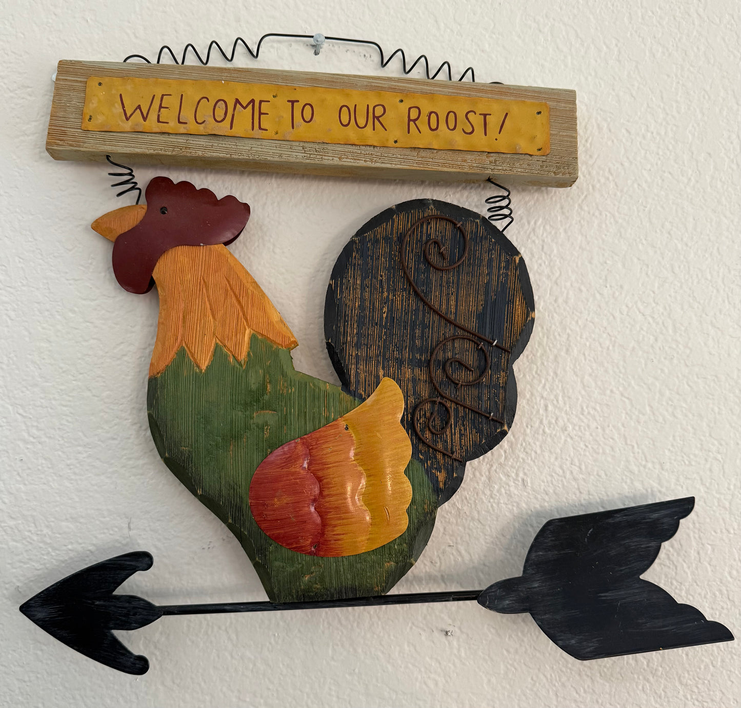 Decorative wall art of a rooster with 'Welcome to our Roost!' sign on a white wall.