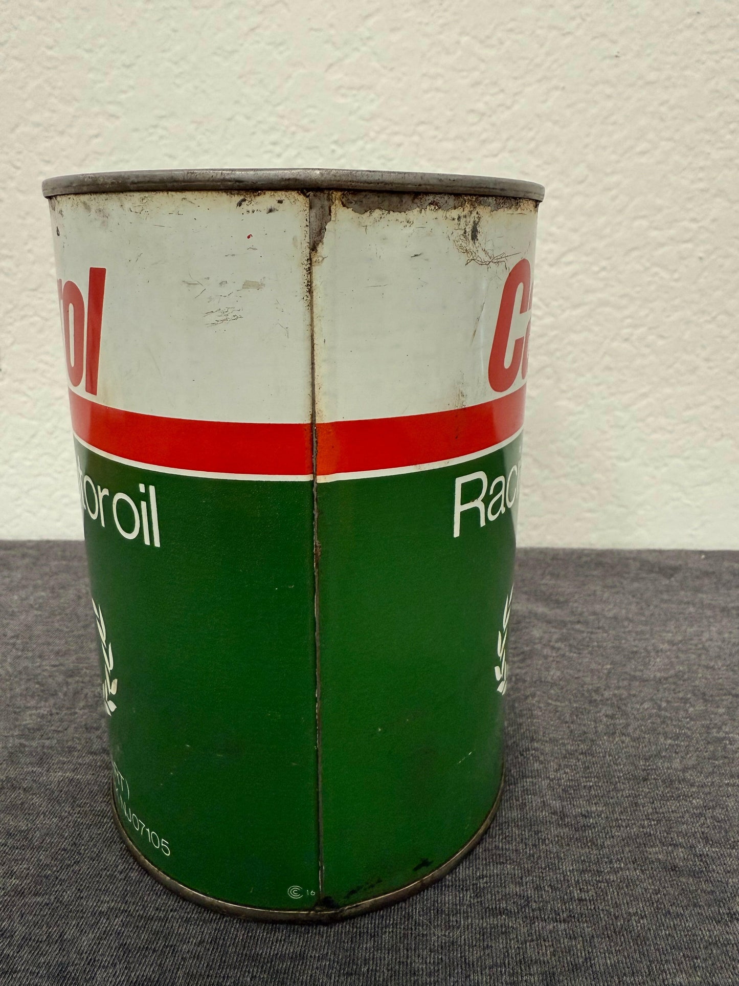 Green and white can with red stripe on a gray surface