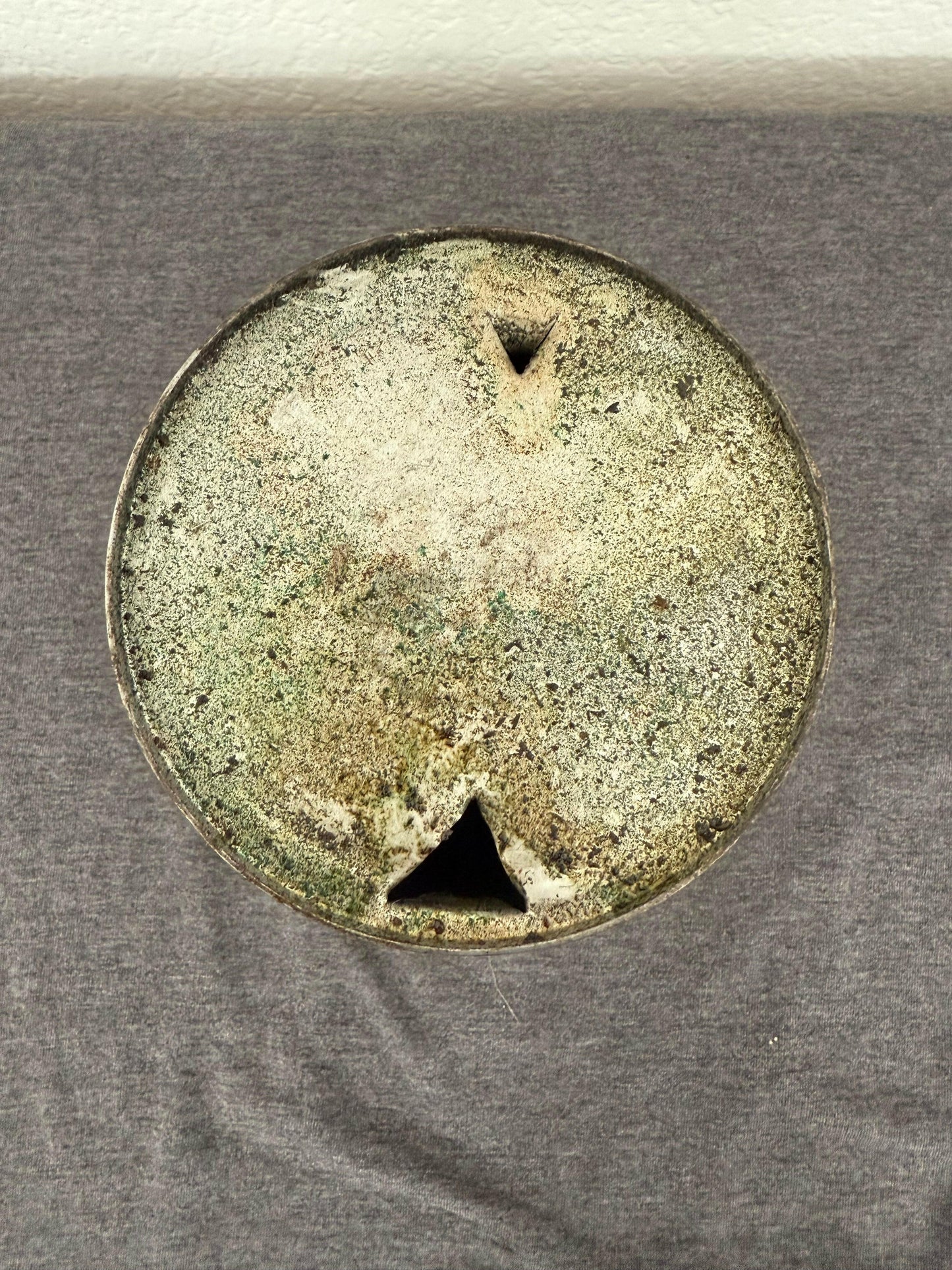 Round metallic object with star-like cutouts on a gray background