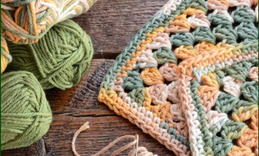 Crocheted blanket with balls of yarn in the background