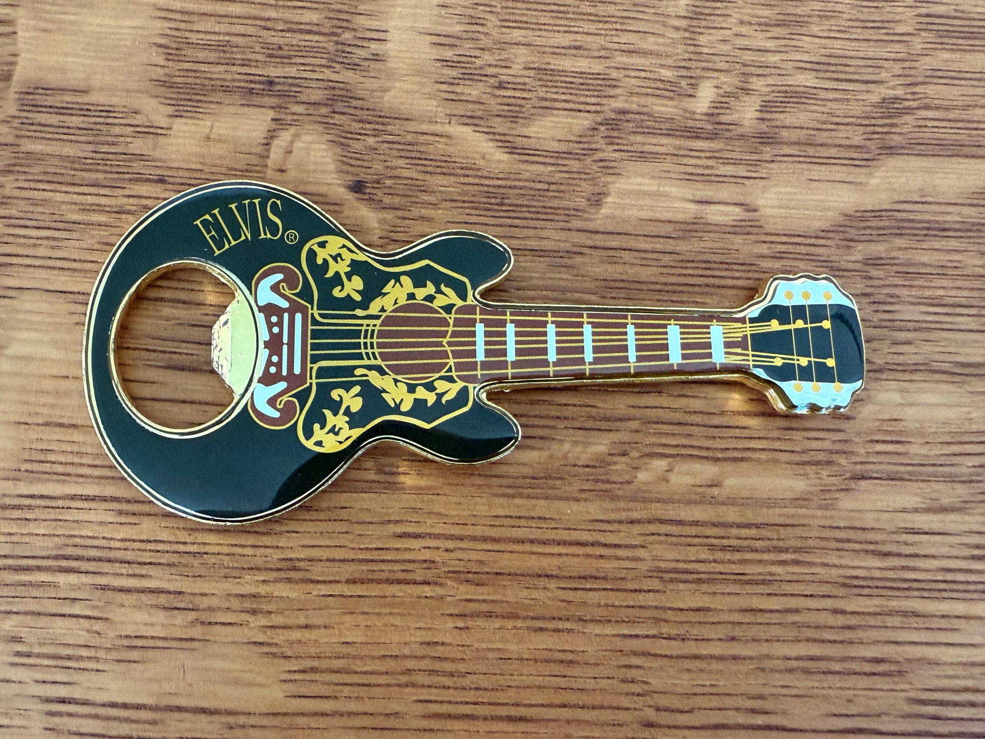Guitar-shaped bottle opener with 'Elvis' branding on a wooden surface
