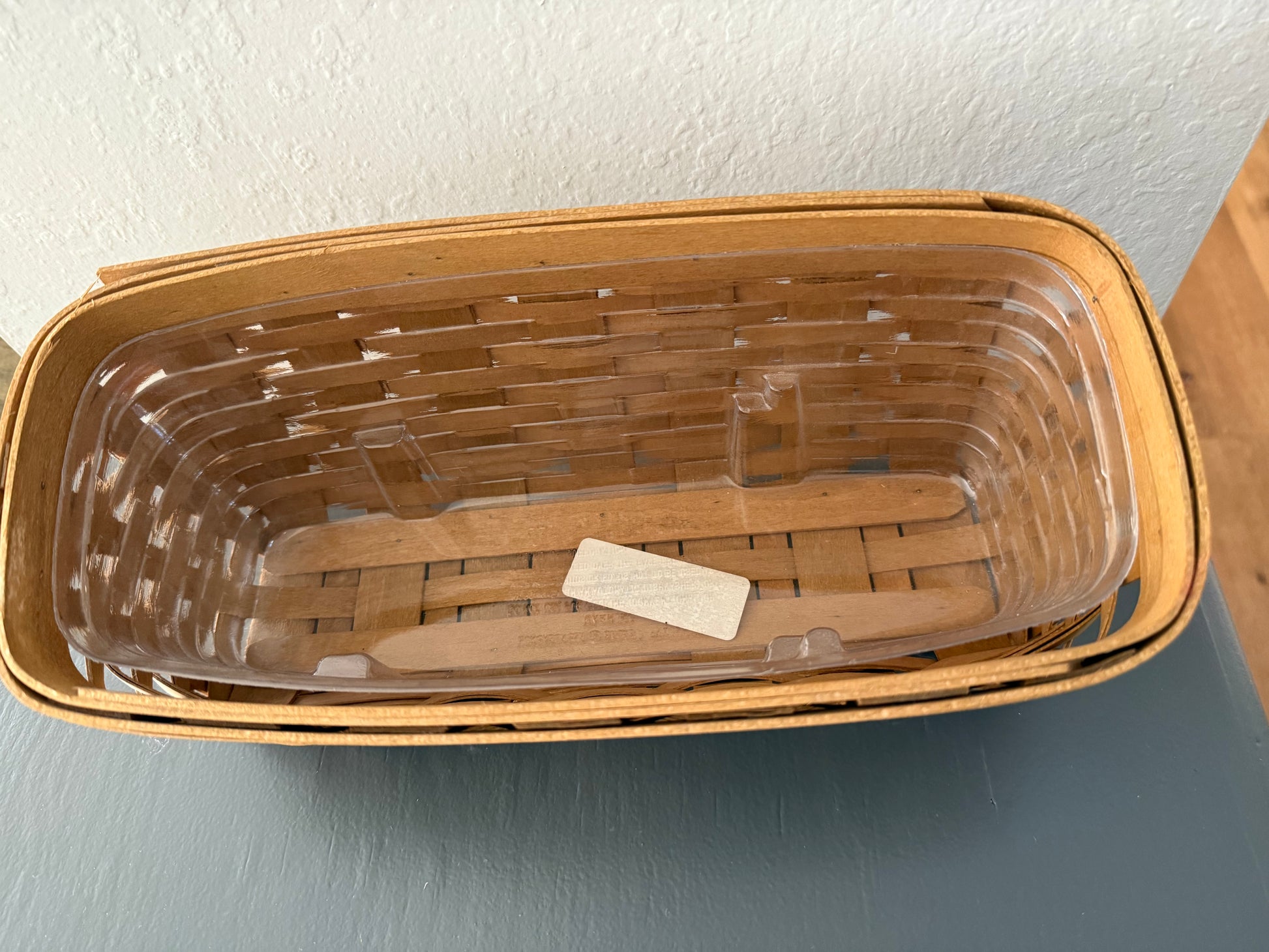 Wicker basket with a clear plastic liner on a gray surface