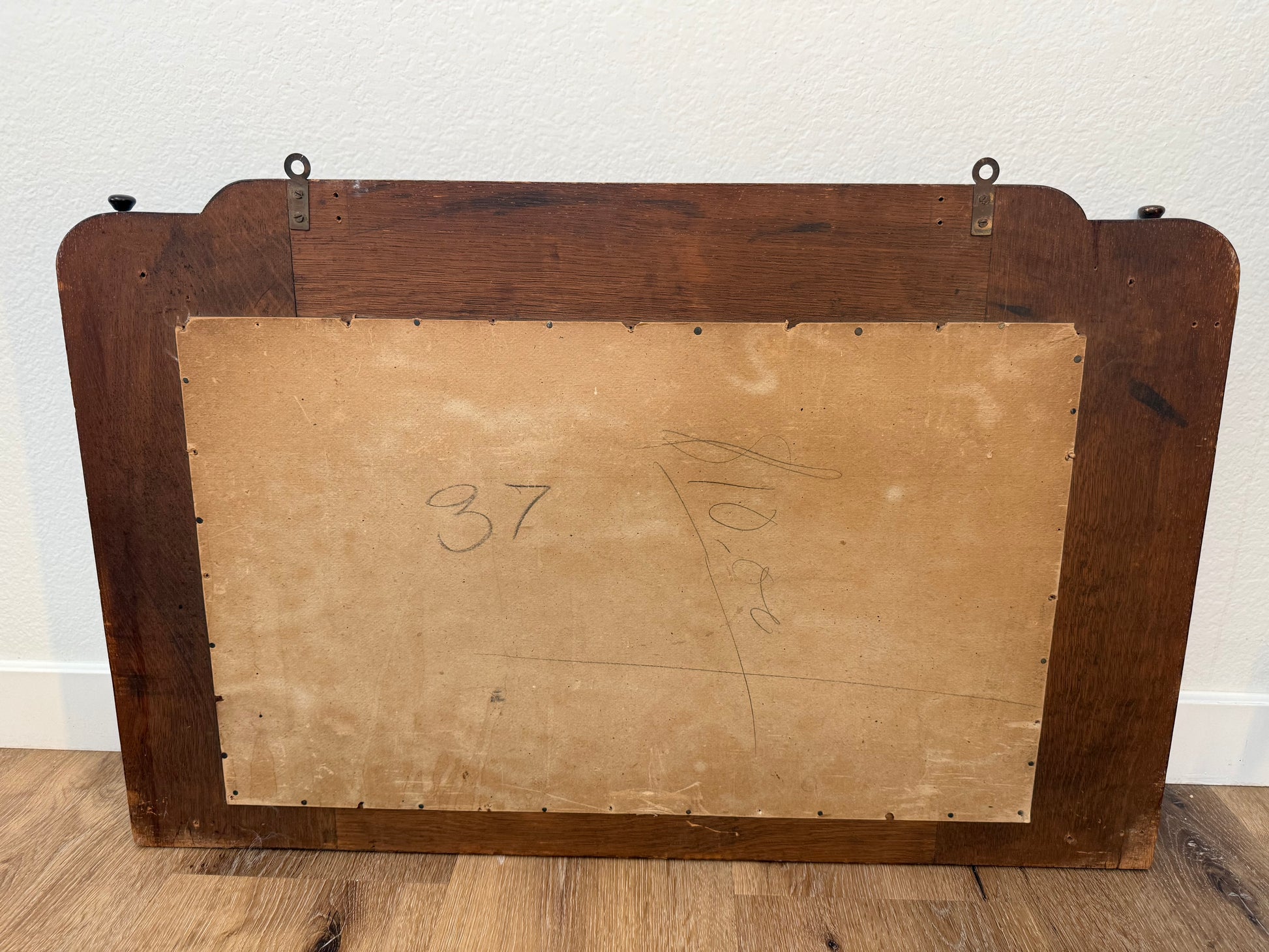 Back of a wood mirror with a wooden frame and a number '37' on a beige canvas.