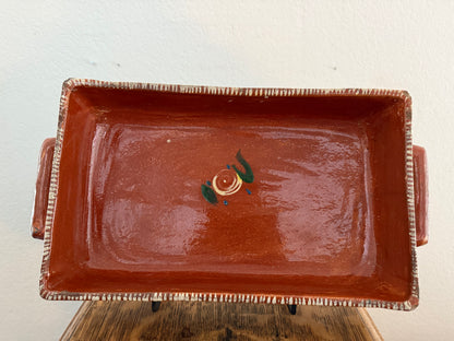 Rectangular brown ceramic dish with decorative elements on a light background