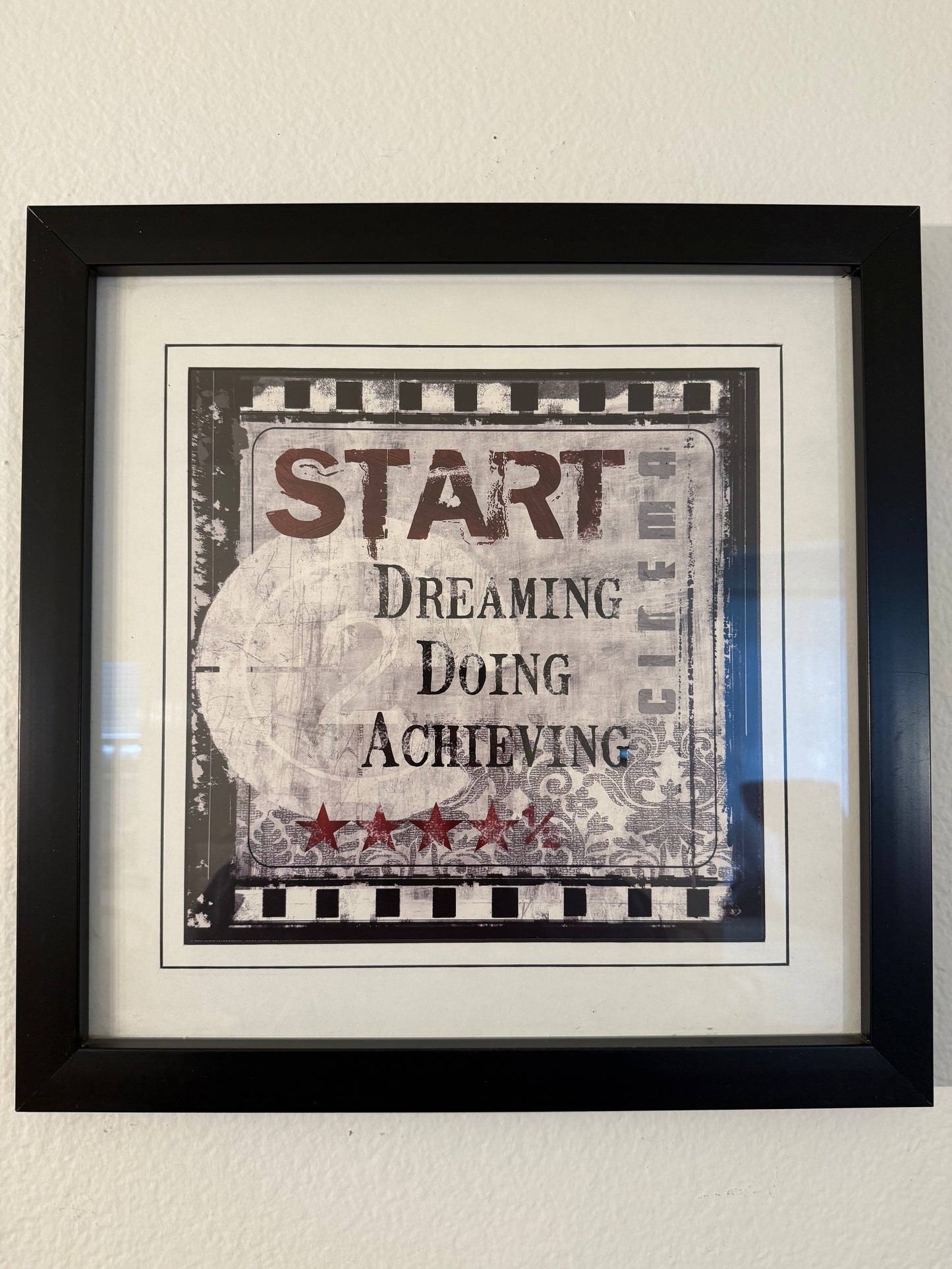 Framed motivational poster with text on a plain wall