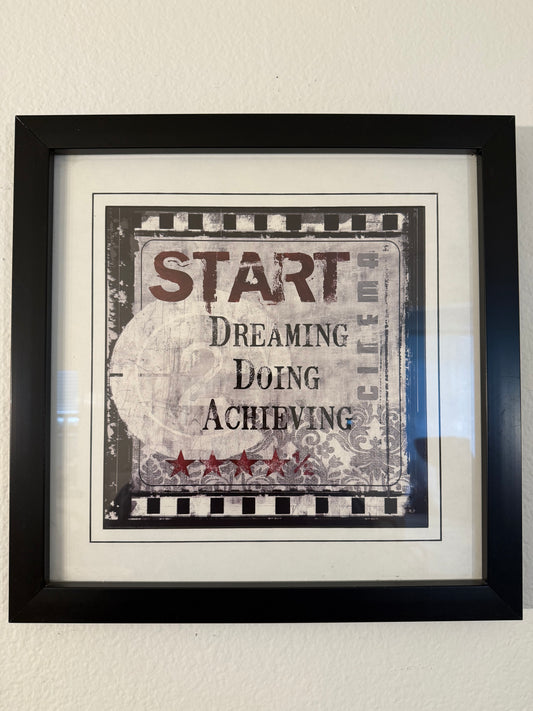 Framed motivational poster with text on a plain wall