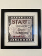 Framed motivational poster with text on a plain wall