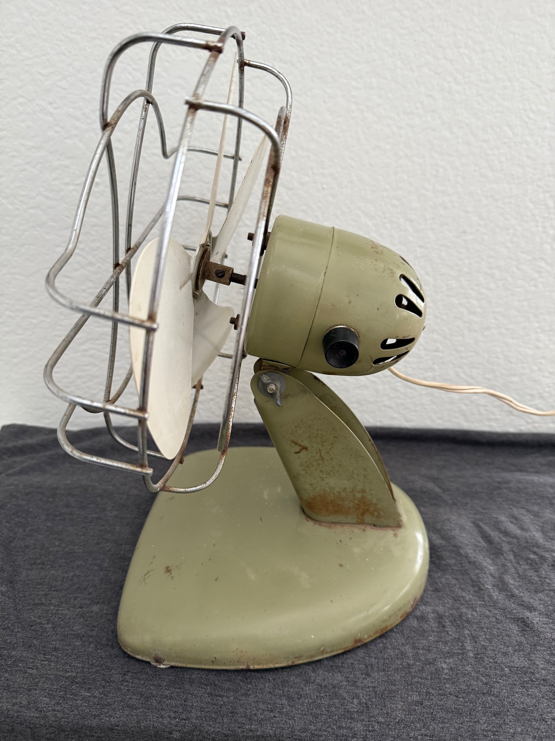 Vintage-style desk fan with white blades and metal frame against a neutral background