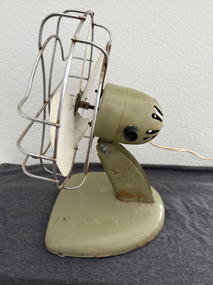 Vintage-style desk fan with white blades and metal frame against a neutral background