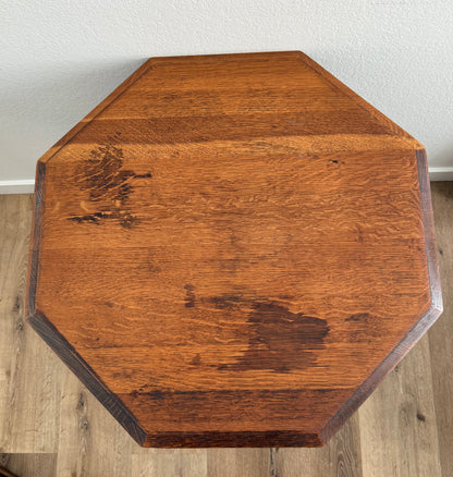 Octagonal wooden table top on a wooden floor with a white wall background