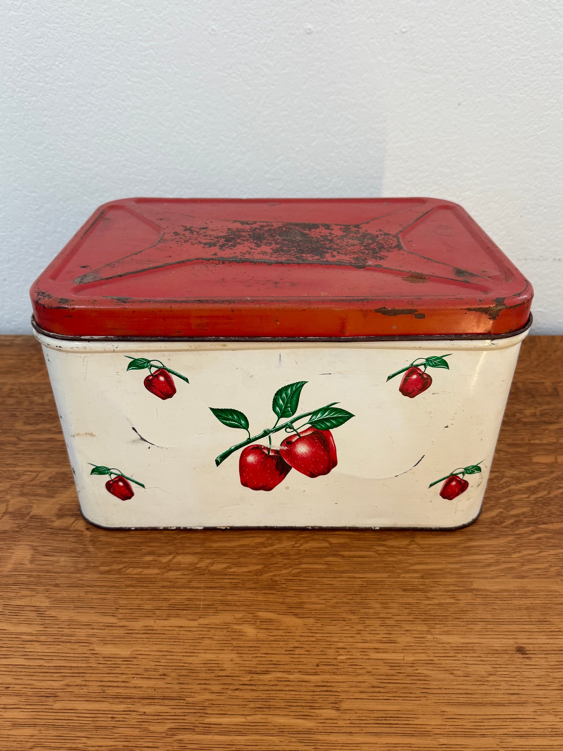 Vintage tin box with red apple design on a wooden surface