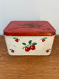 Vintage tin box with red apple design on a wooden surface