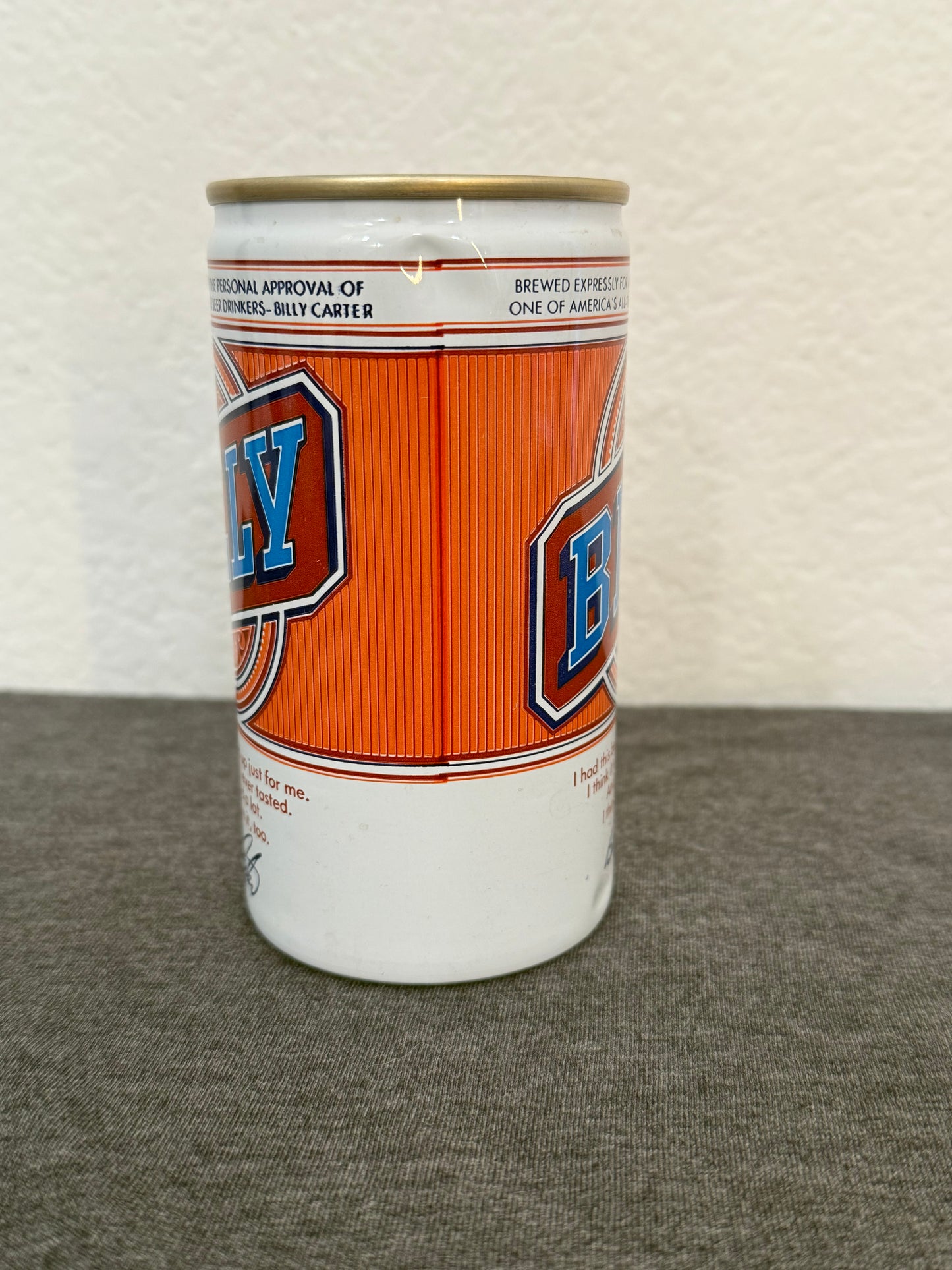 Cylindrical container with orange and white design on a textured surface