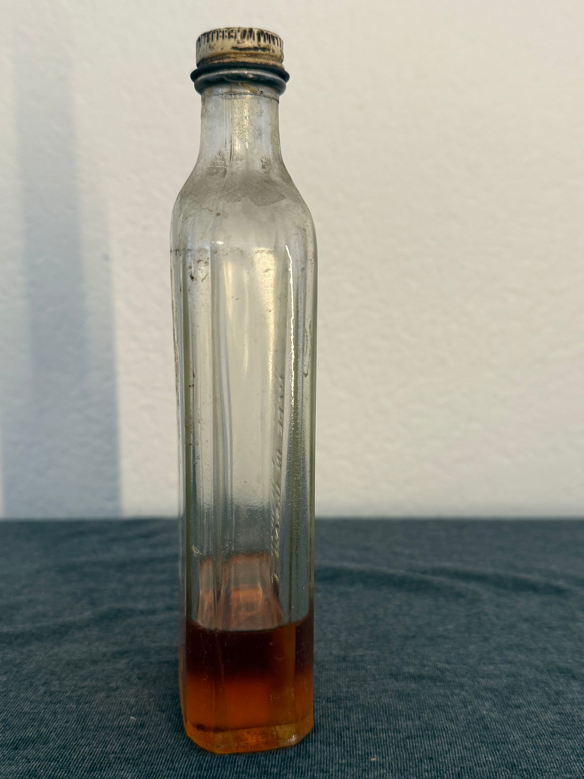 Clear glass bottle with a brownish-red liquid on a white background