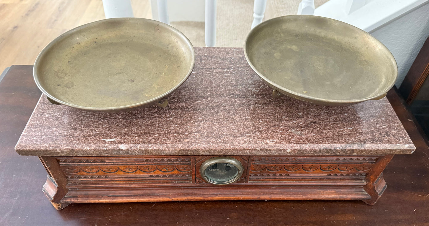 Two brass plates on an ornate wooden stand with a scale.