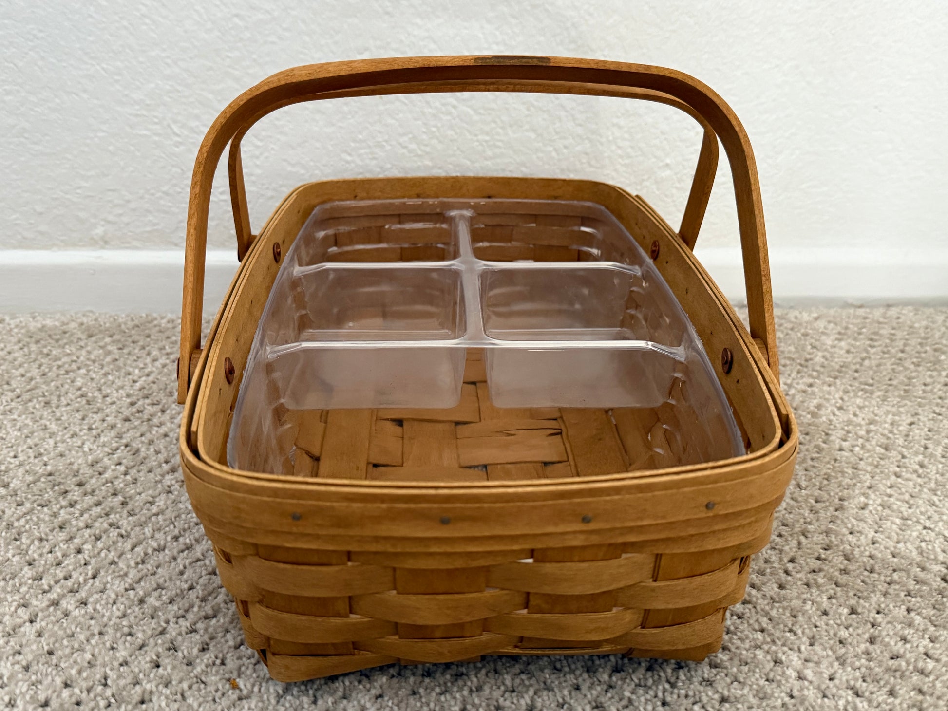 Bamboo basket with a clear plastic interior on a carpeted floor.
