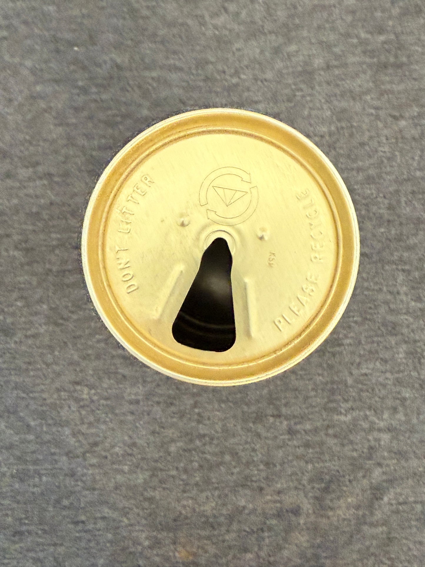 Gold-colored lid with a black central feature on a gray background