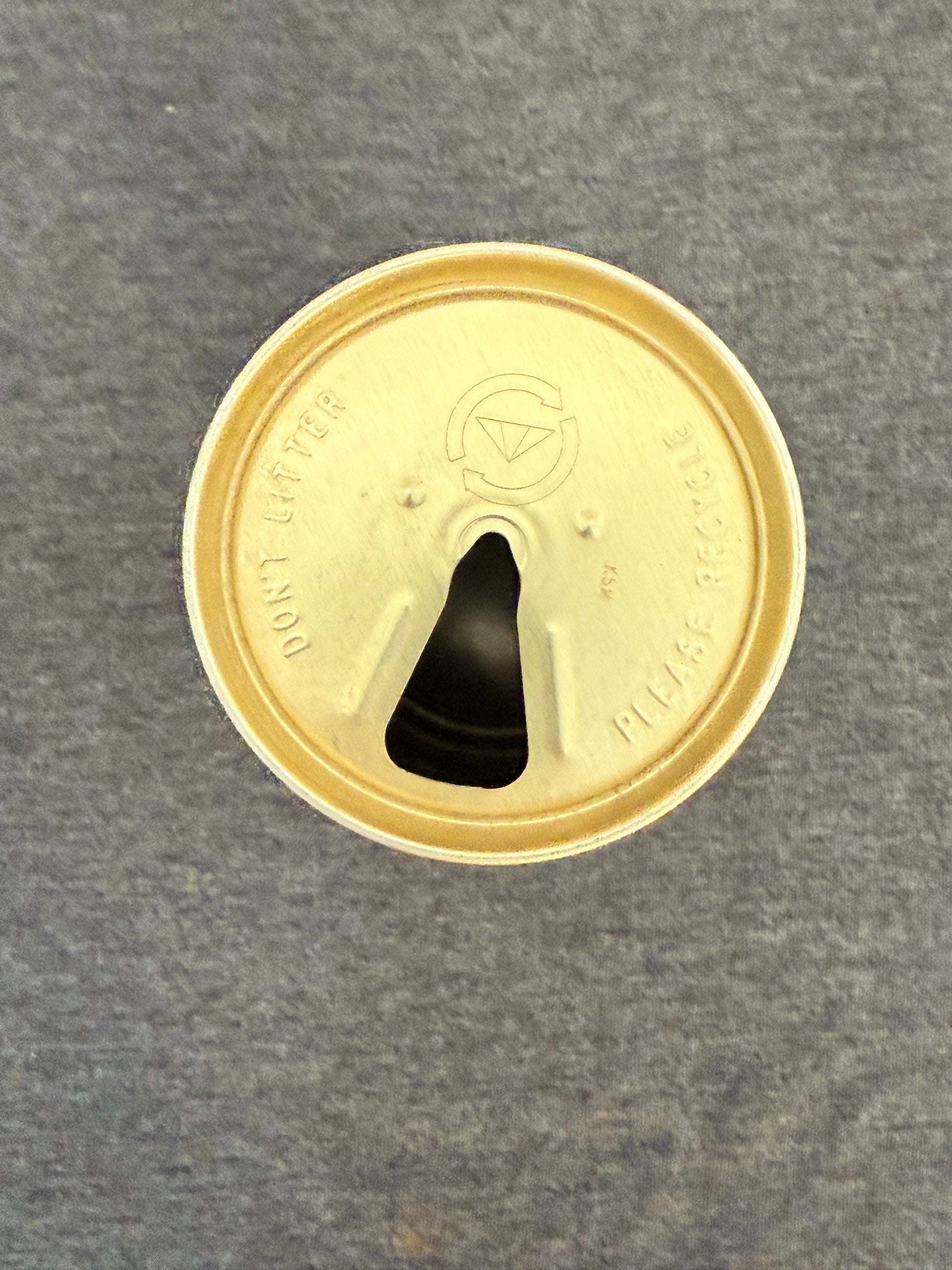 Gold-colored lid with a black central feature on a gray background