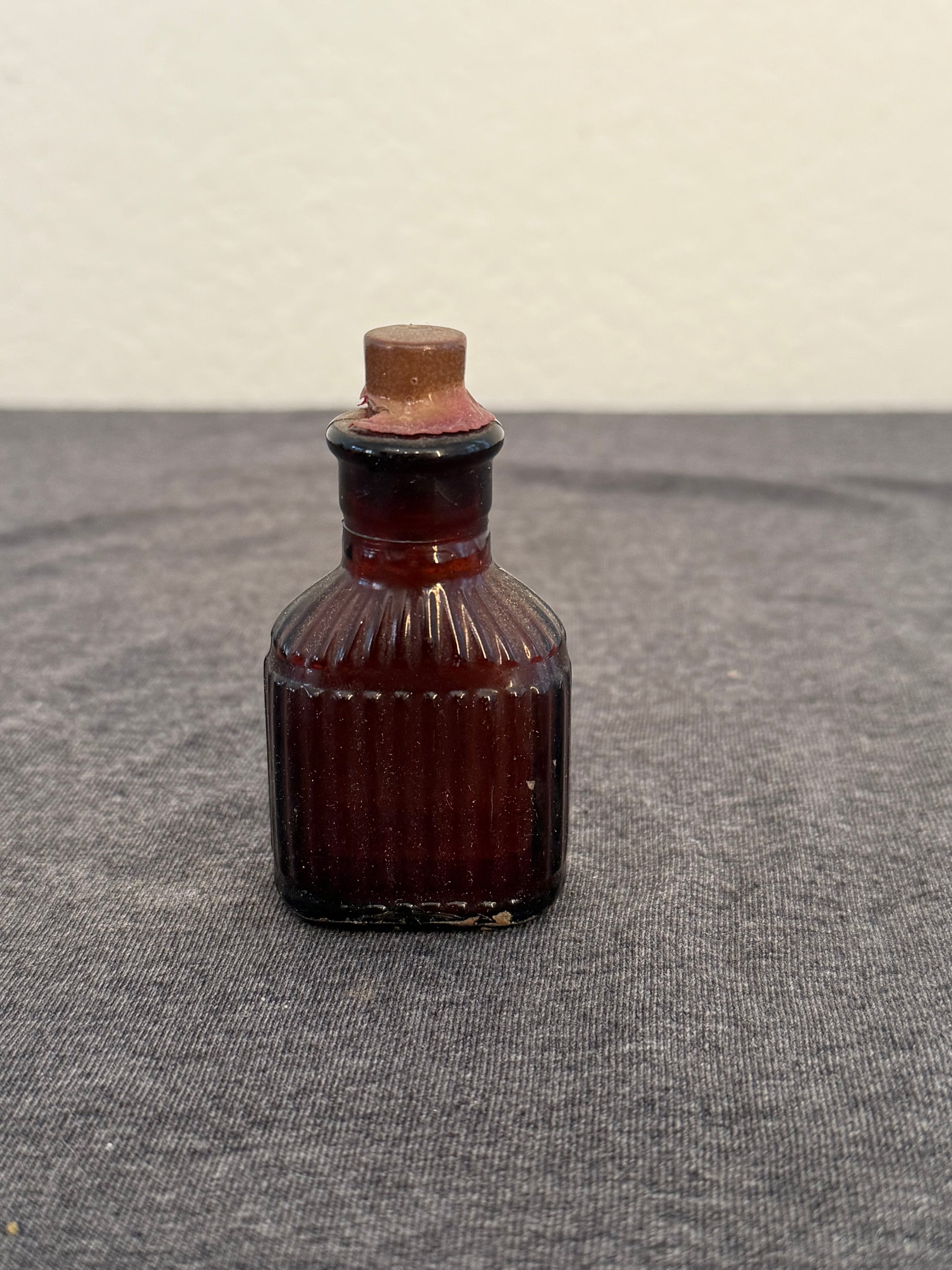 Small brown glass bottle with a ribbed design on a gray surface
