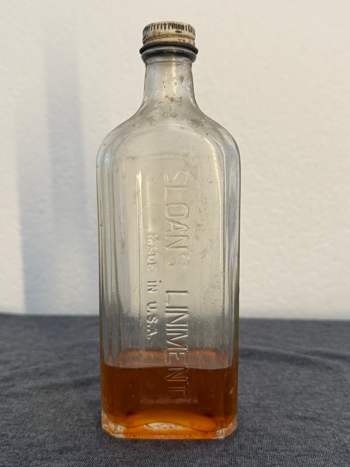 Vintage glass bottle labeled 'Sloan's Liniment' on a gray background