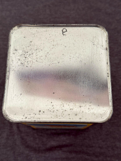 Metallic square object with speckled texture on a dark background