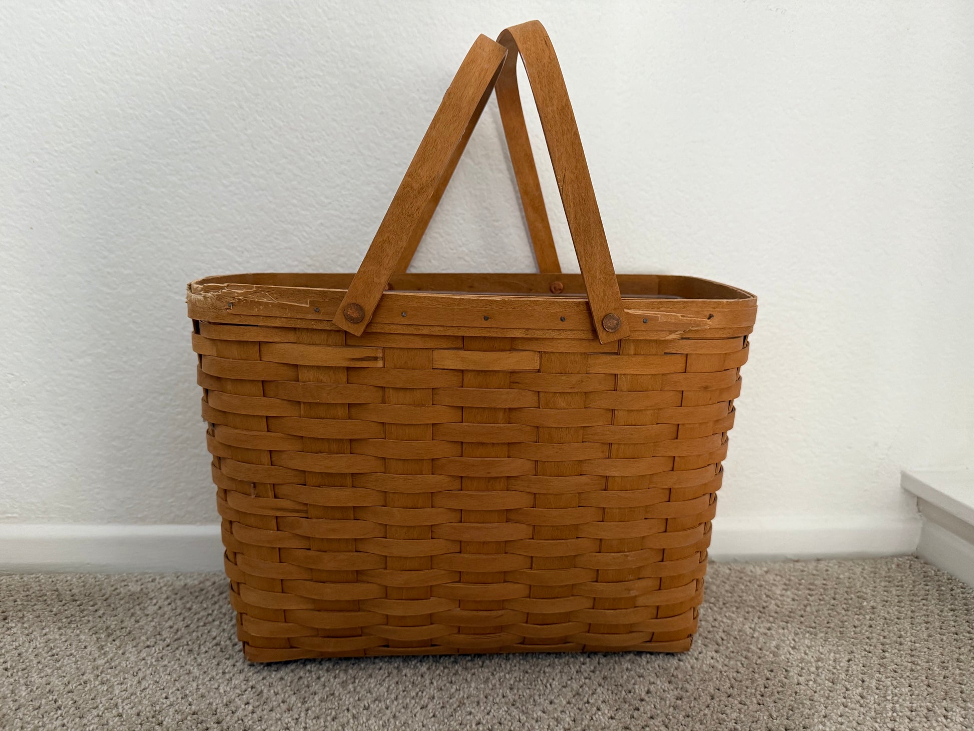 Brown woven basket with handles on a plain background