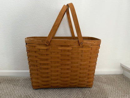 Brown woven basket with handles on a plain background