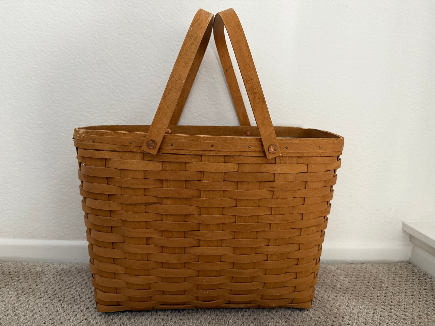 Brown woven basket with handles on a neutral background