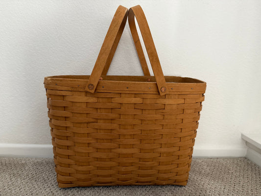 Brown woven basket with handles on a neutral background