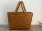 Brown woven basket with handles on a neutral background