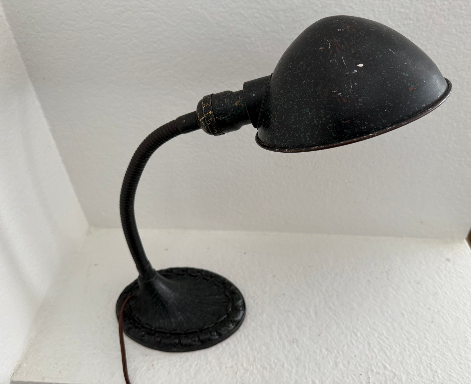 Vintage-style black desk lamp on a white surface with a white wall background