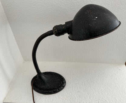 Vintage-style black desk lamp on a white surface with a white wall background