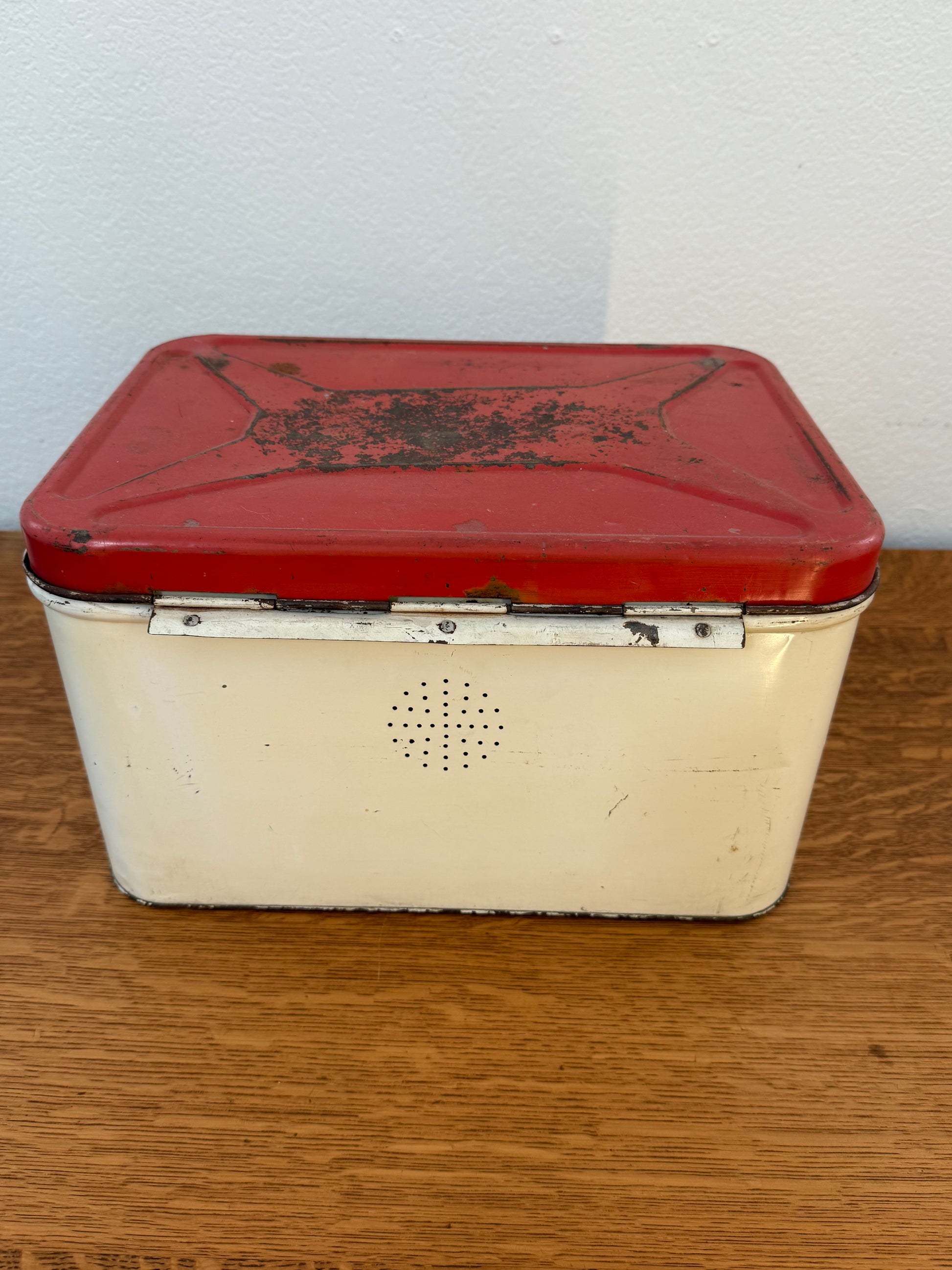 Vintage red and white tin on a wooden surface with white wall background