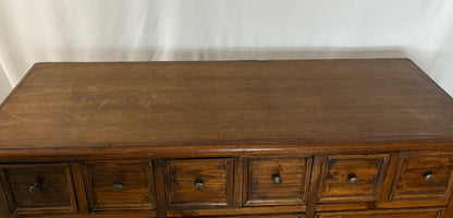 Wooden dresser with multiple drawers against a white background
