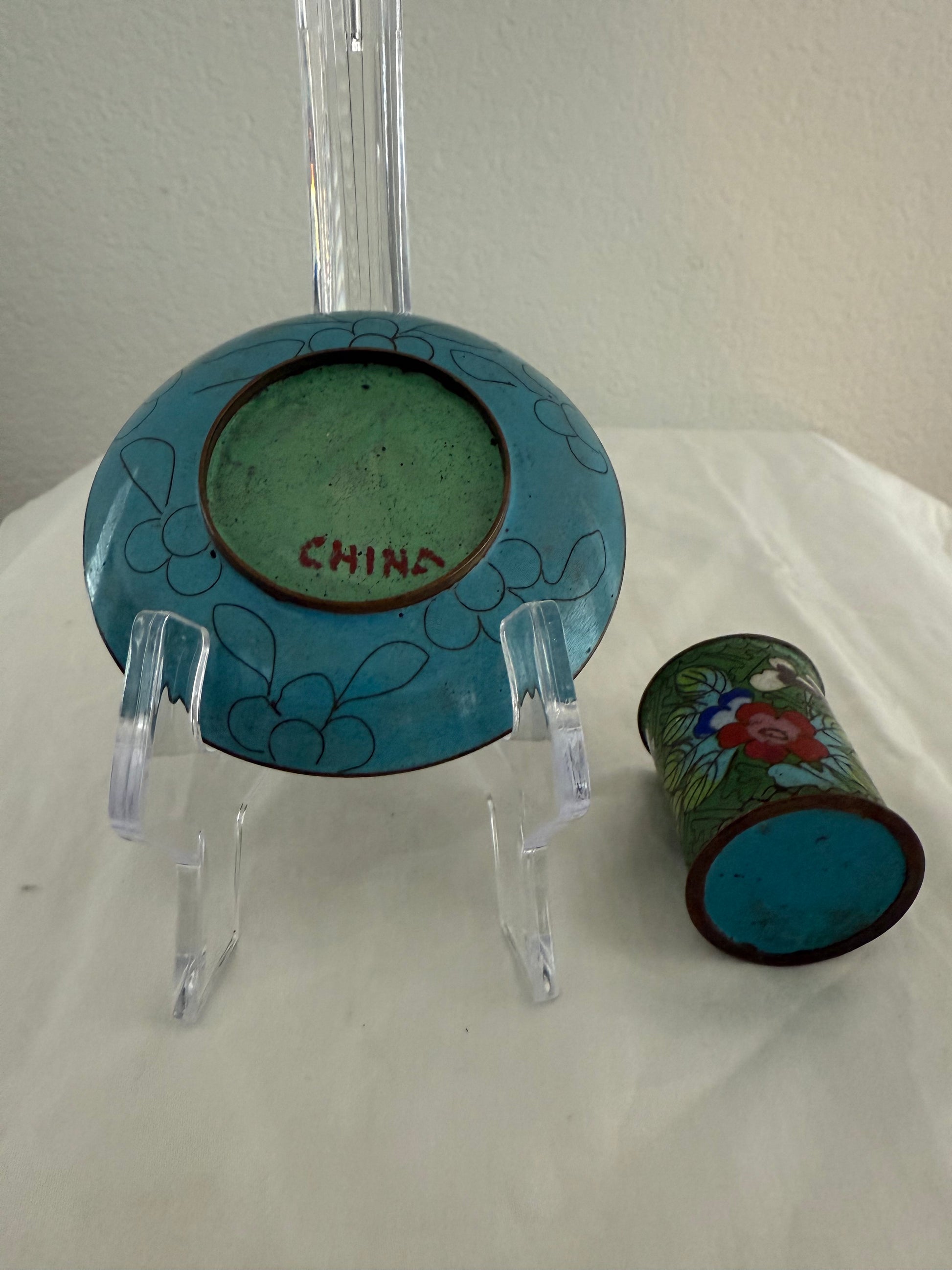 Small ceramic plate and cup with floral designs on a white surface.